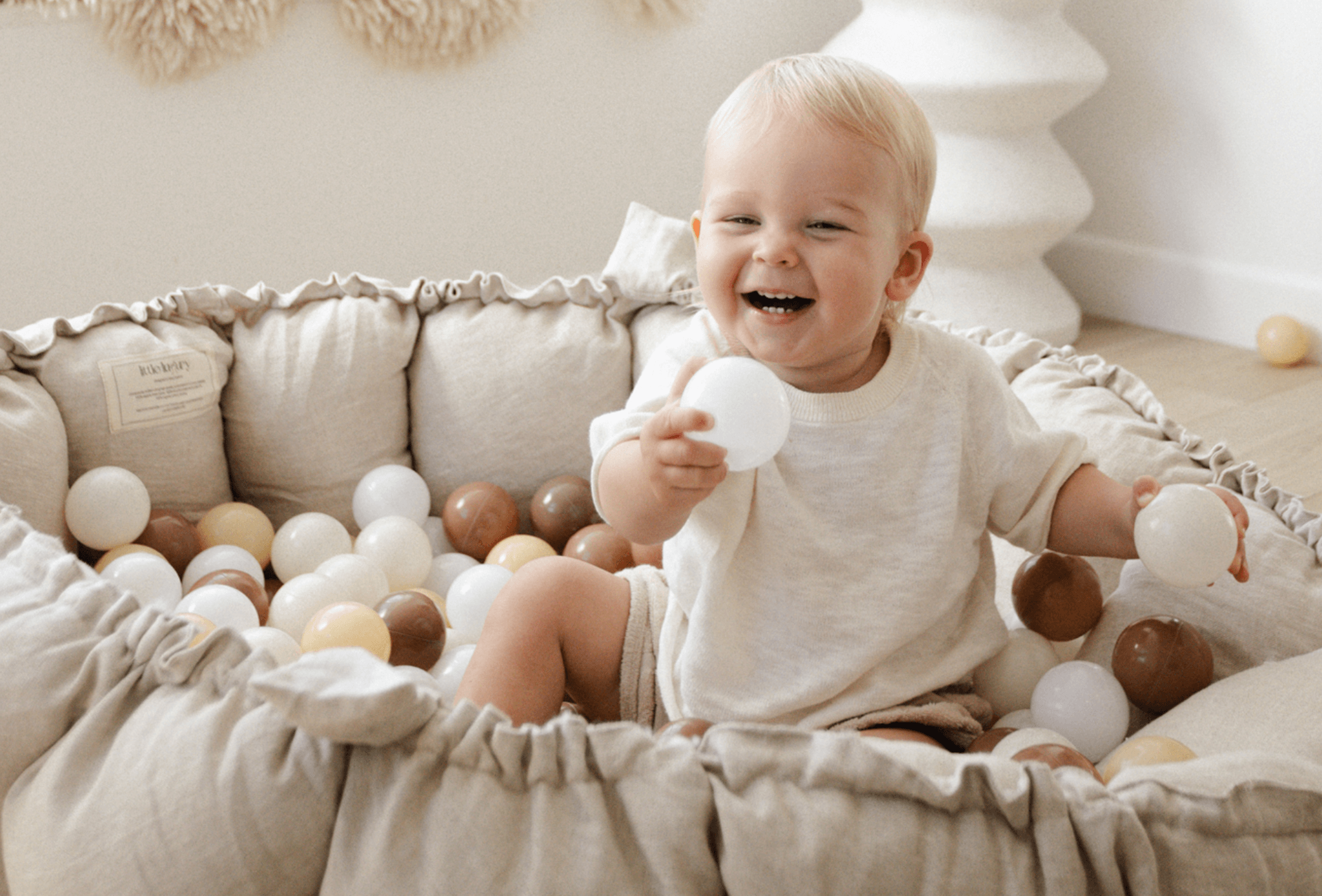Baby lying on a soft, organic cotton Little Luxury playmat in a sunlit room, surrounded by calm, neutral tones — designed for tummy time, play, and everyday comfort.